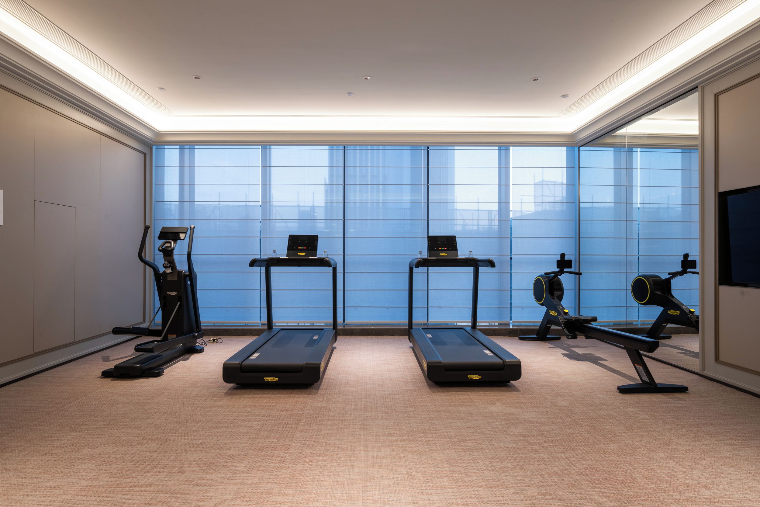 Un gimnasio equipado con cintas de correr, una bicicleta estática y una máquina de remo.