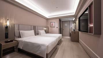 Habitación de hotel con dos camas, una mesita de noche, televisión y puerta de baño.