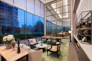 Una habitación amplia con ventanas grandes, un comedor y una estantería.