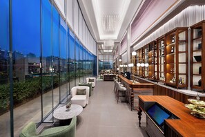 A modern bar area with a city view, seating, and a wine display. - Mercure Shanghai Lujiazui Binjiang Center (Shanghai)