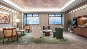 A spacious living room with a high ceiling, large windows, and a bar area.