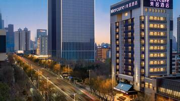 A modern hotel with a prominent sign, surrounded by high-rise buildings and a busy street.