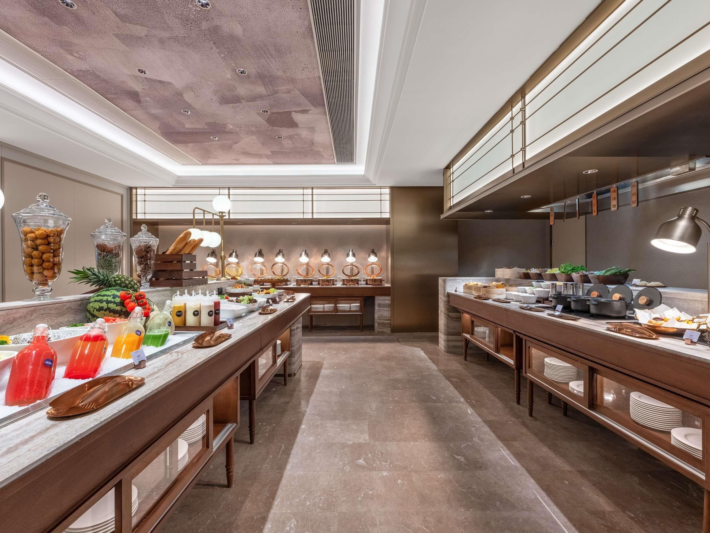 Una cocina amplia con una encimera larga, diversos alimentos y luminarias modernas.