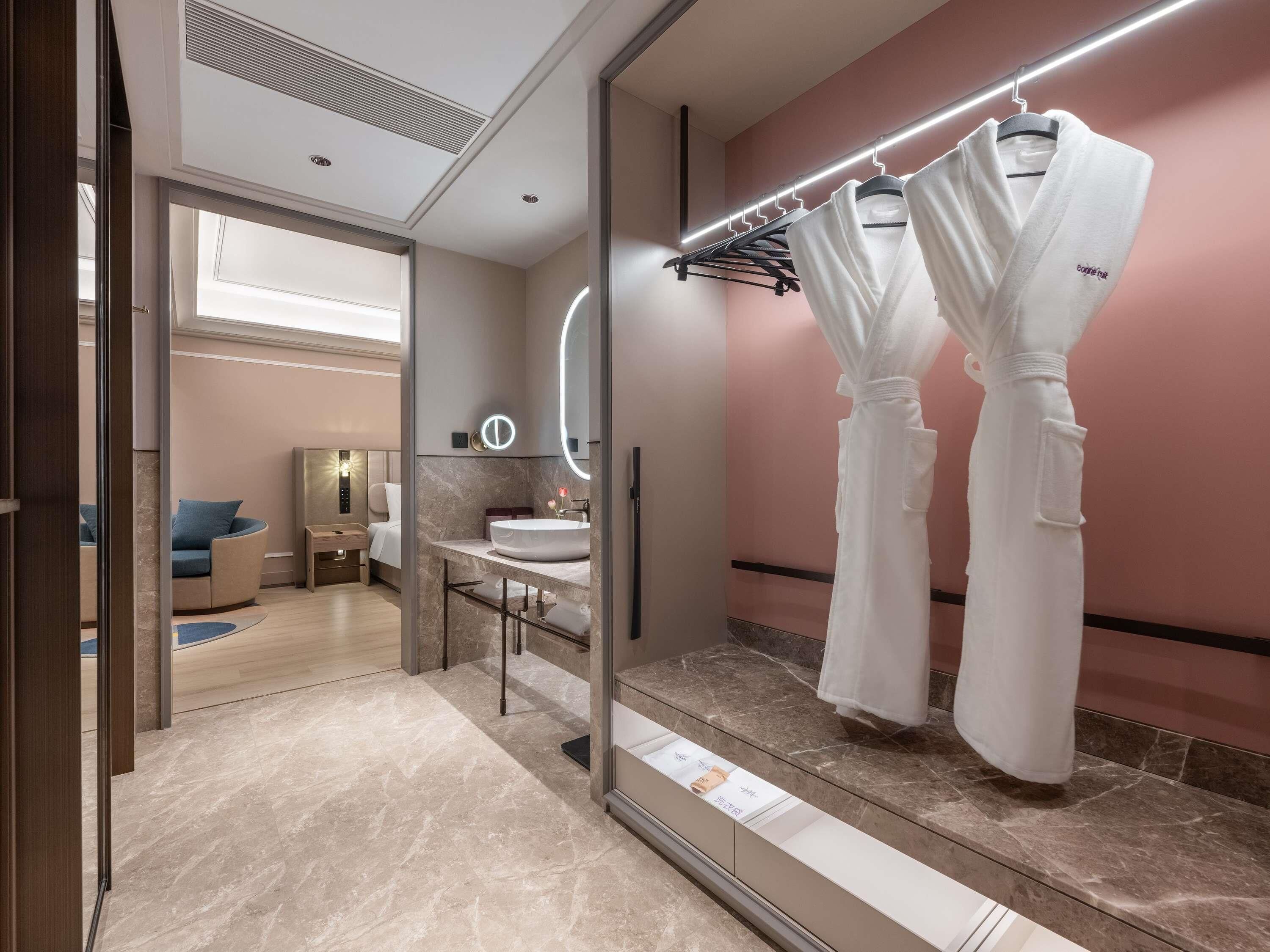 A modern bathroom with a vanity, mirror, and robe hooks.