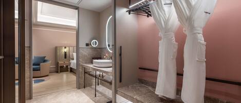 A modern bathroom with a vanity, mirror, and robe hooks.