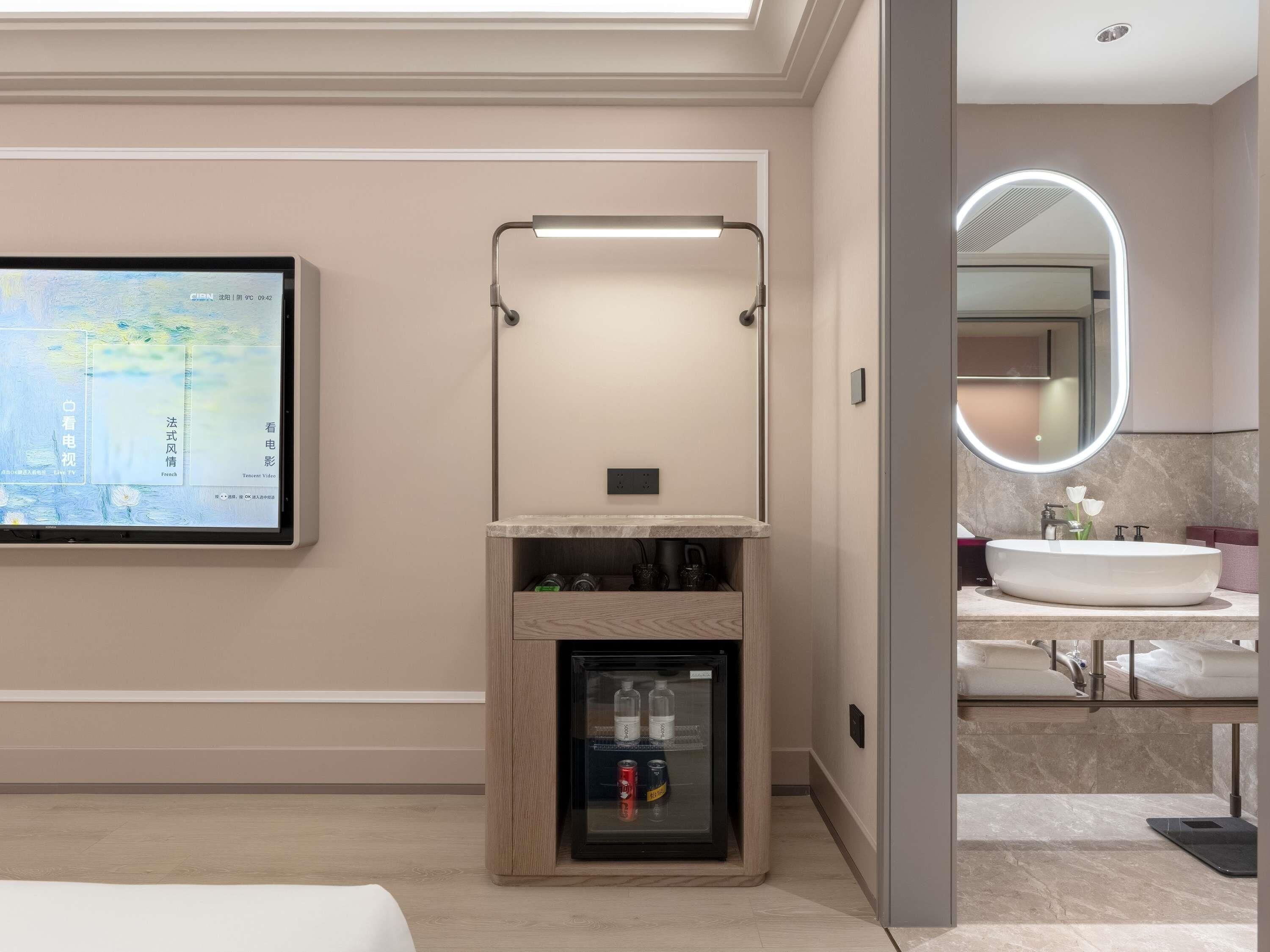 A modern bathroom with a large mirror, a sink, and a built-in refrigerator.