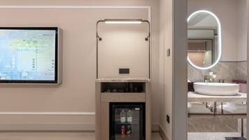 A modern bathroom with a large mirror, a sink, and a built-in refrigerator.