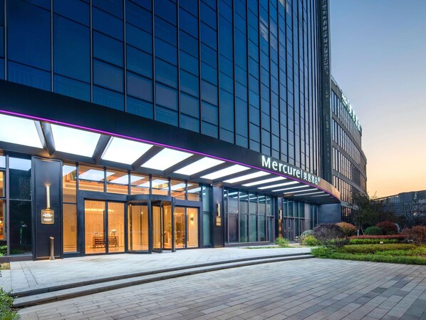 A modern hotel entrance with a glass facade, a covered entrance area, and a sign reading 'Mercure'. - Mercure Wuxi Tian'An Intelligent Park (Wuxi)