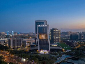 A modern hotel with a unique curved facade, surrounded by a well-maintained urban landscape.