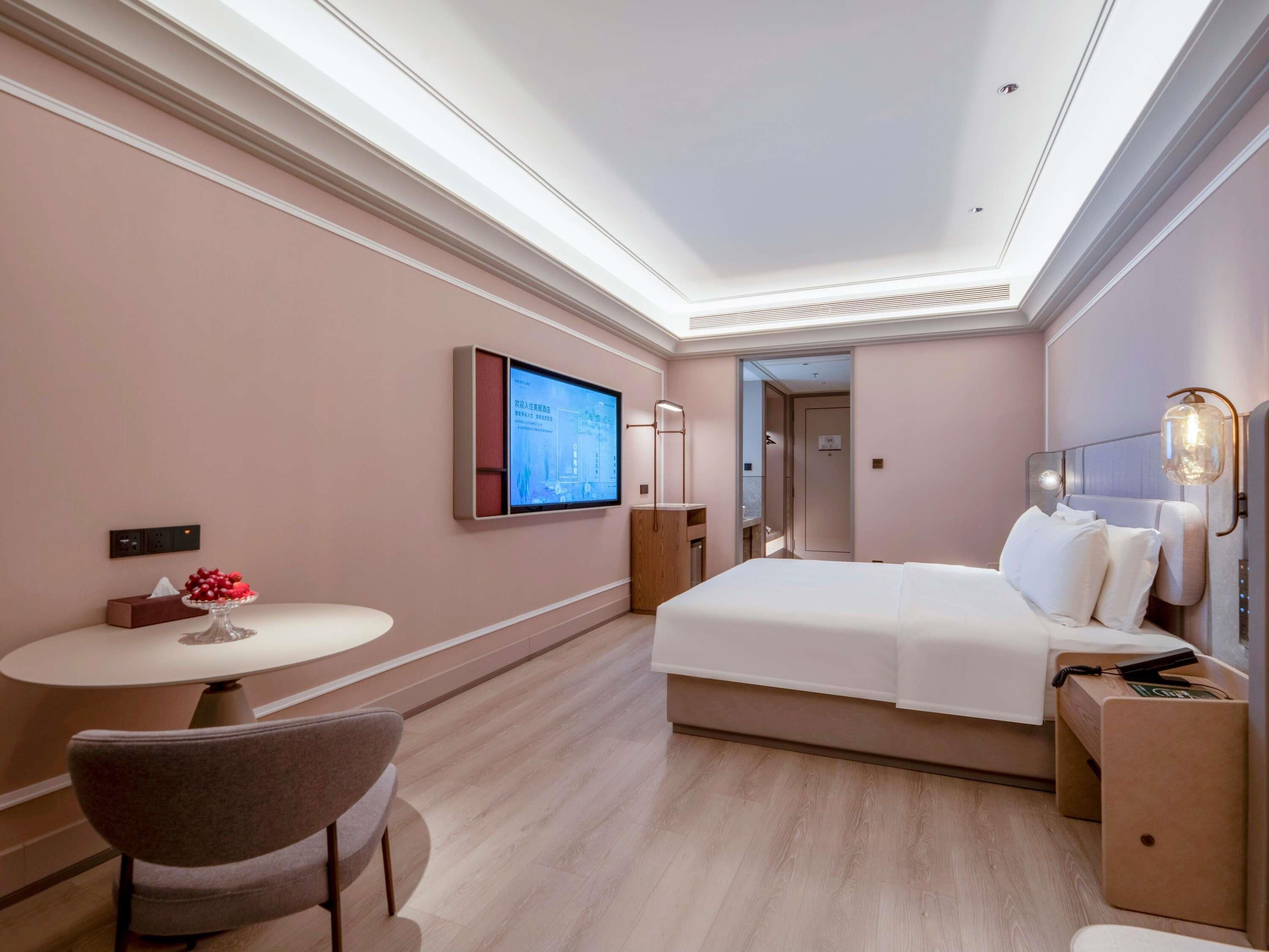 Een hotelkamer met een bed, een bureau, een stoel, een televisie en een nachtkastje.