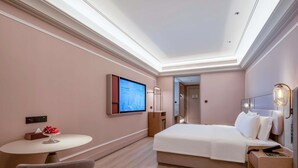 Una habitación de hotel con una cama, un escritorio, una silla, un televisor y una mesita de noche.