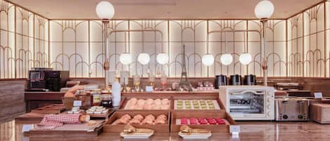 Mostrador de panadería con pasteles, una máquina de café y una radio antigua.
