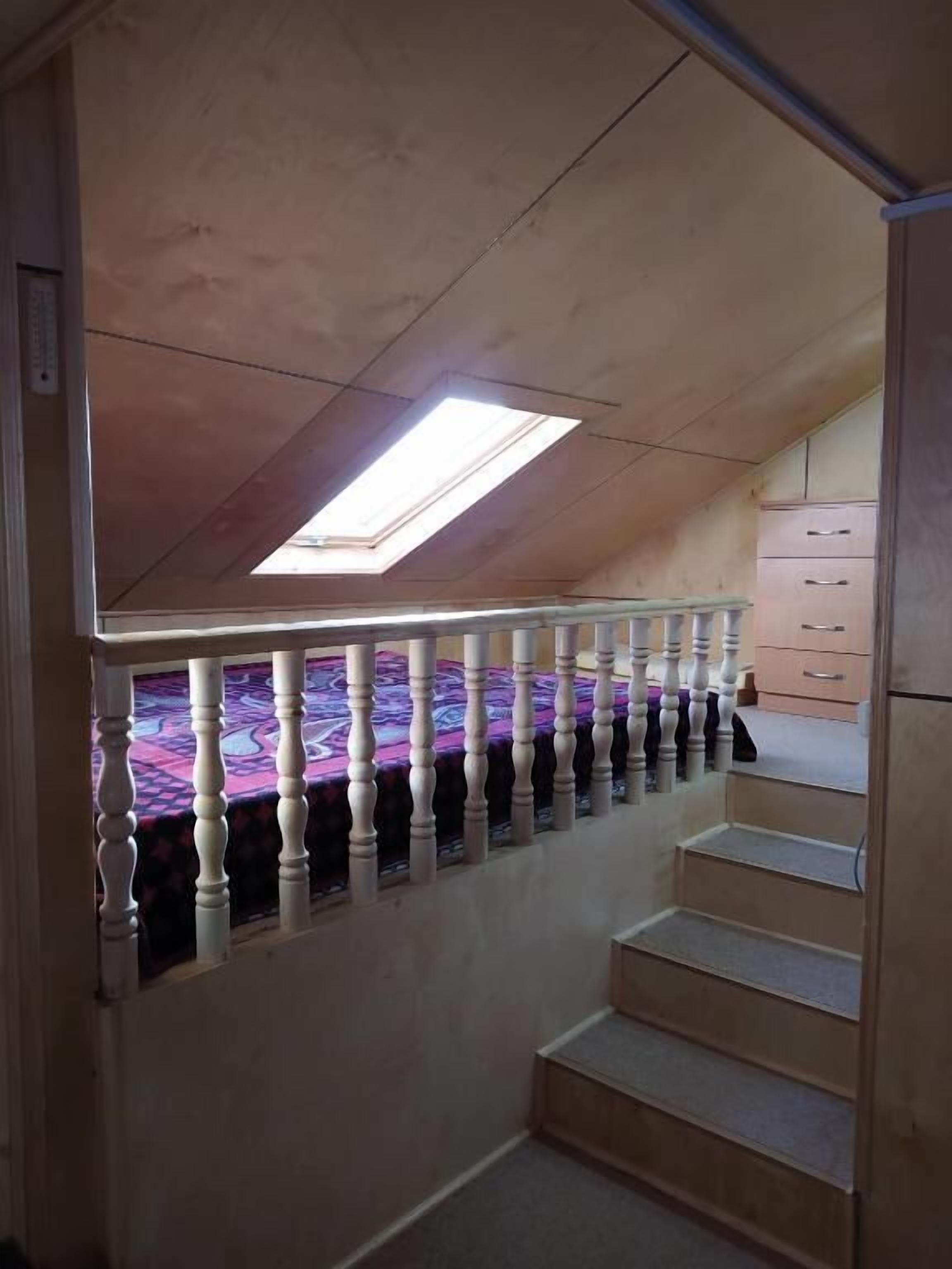 A staircase with a skylight, carpeted steps, and a white railing.