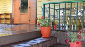 A wooden staircase leading to a door, a metal railing, and potted plants.