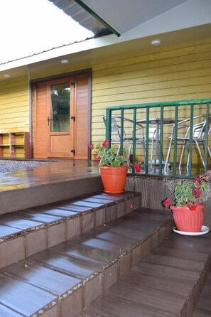 A wooden staircase leading to a door, a metal railing, and potted plants.