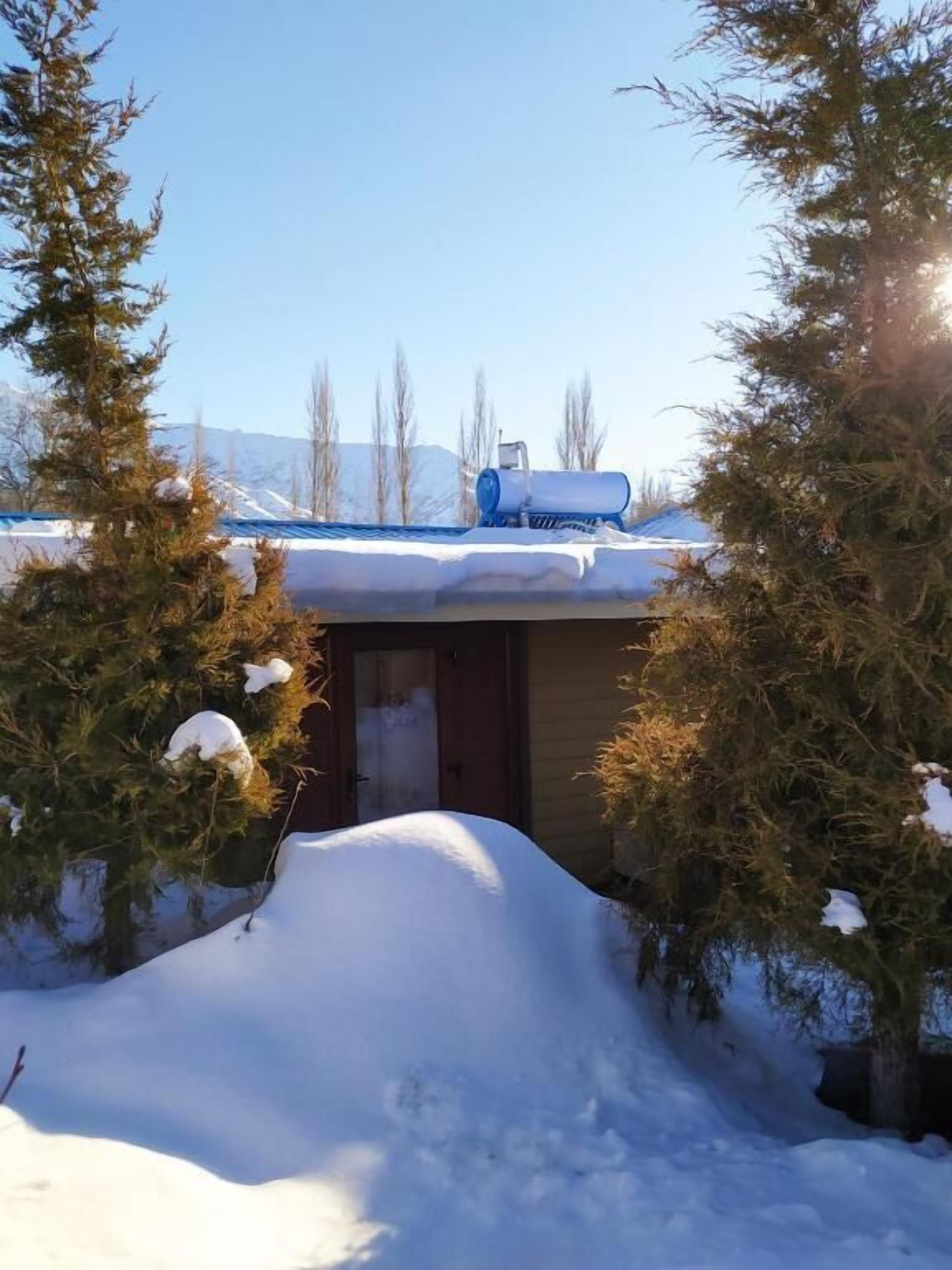 A snow-covered building with a blue roof, surrounded by trees and a snowbank.
