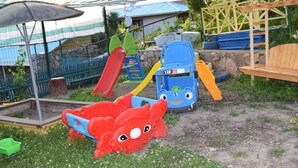 A children's play area with a slide, climbing structures, and a bench.