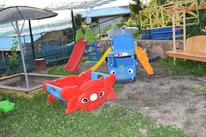 A children's play area with a slide, climbing structures, and a bench.