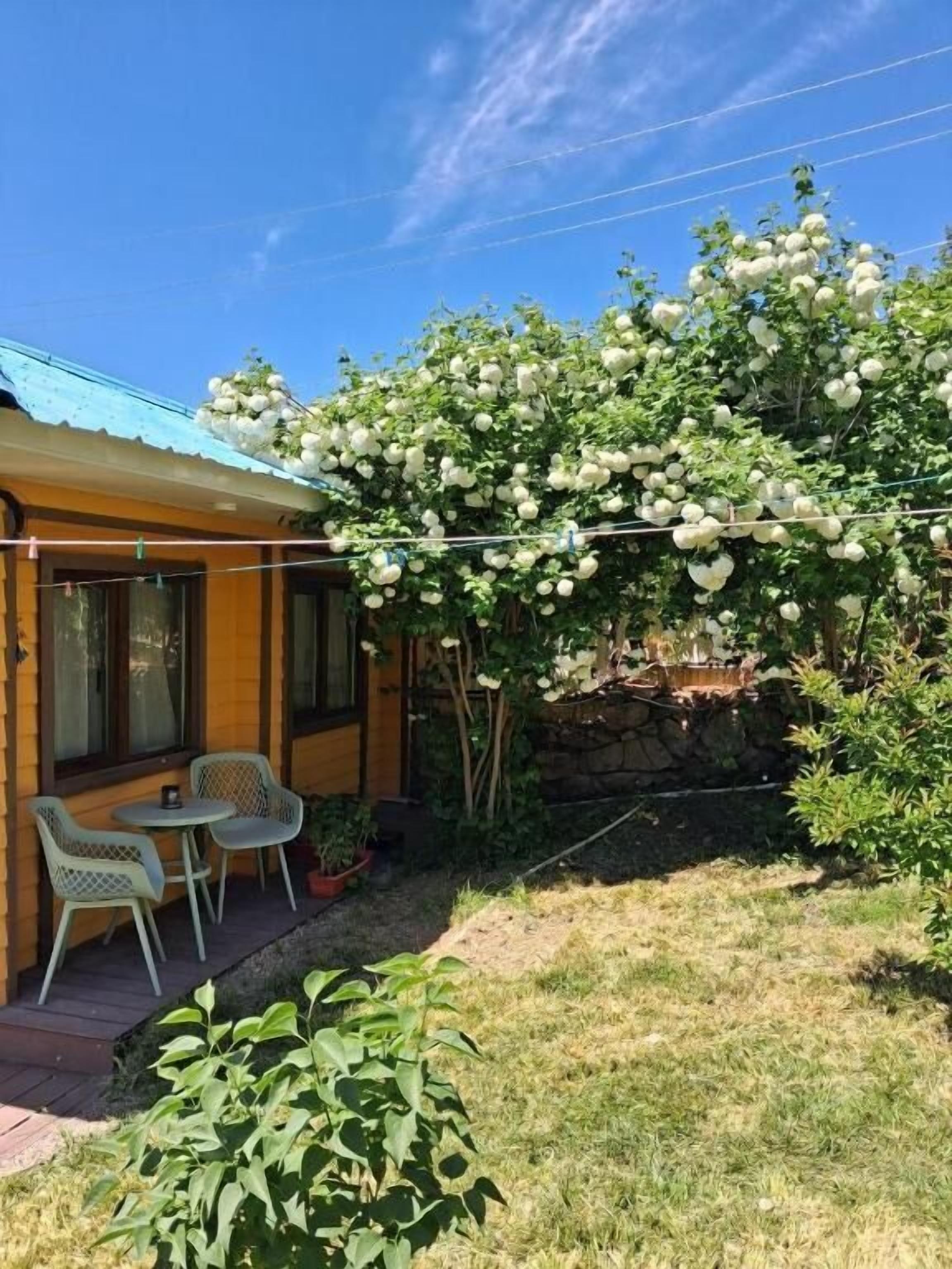 Una casa de madera con un porche techado, una mesita y sillas.