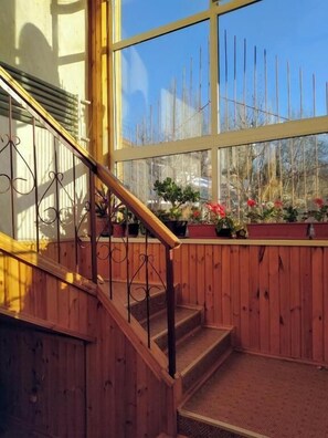 A wooden staircase with a metal railing leading to a landing area with potted plants.