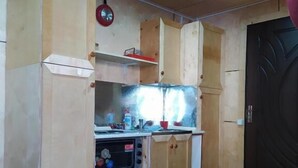 A compact kitchen with wooden cabinets, a built-in oven, and a black door.