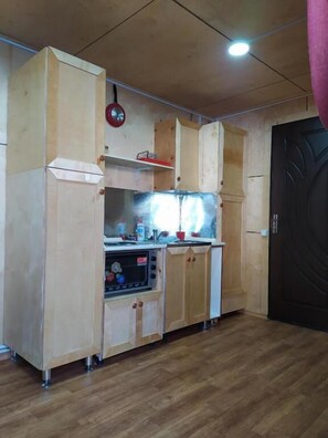 A compact kitchen with wooden cabinets, a built-in oven, and a black door.