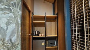 A compact kitchen with a refrigerator, microwave, and kettle.