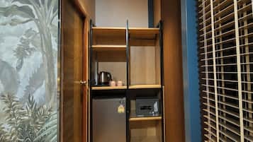 A compact kitchen with a refrigerator, microwave, and kettle.