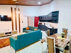 A modern living room with a sofa, a dining table, and a kitchen area with cabinets. -  1-BR Bright & Quite Apartment & Large Living Room (Accra)
