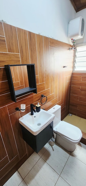 A bathroom with a wooden panel wall, a white sink, a toilet, and a towel rack. -  1-BR Bright & Quite Apartment & Large Living Room (Accra)