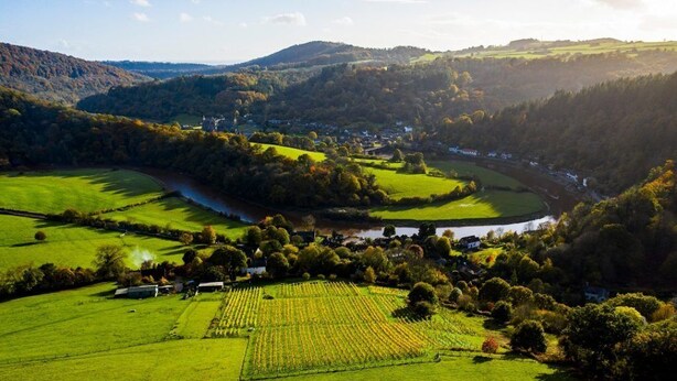 A rural landscape with fields, a river, and a small village.