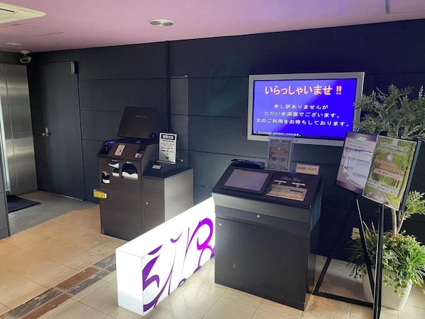 A reception area with a digital display, a reception desk, and a signboard.