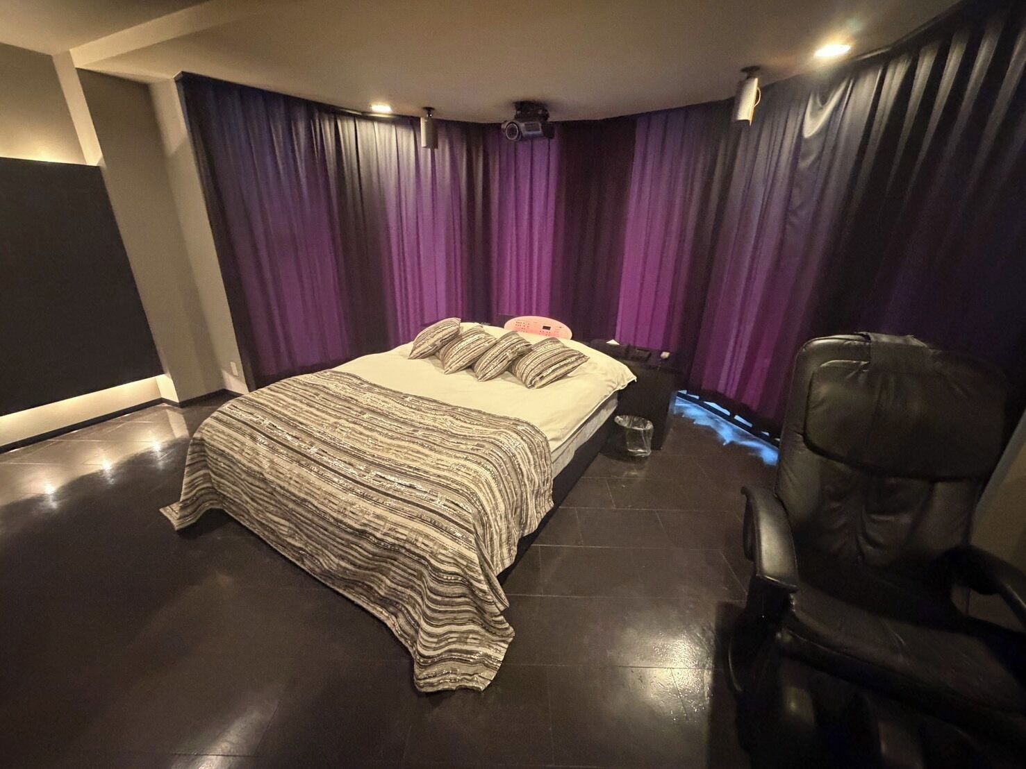 A bedroom with a bed, a chair, and purple curtains.