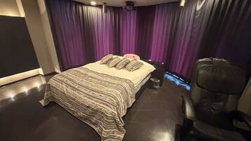A bedroom with a bed, a chair, and purple curtains.