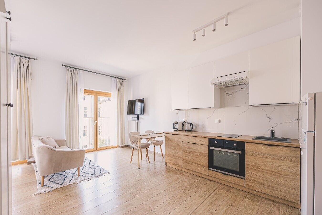 Una cocina moderna con armarios de madera, horno integrado y un comedor con mesa y sillas.