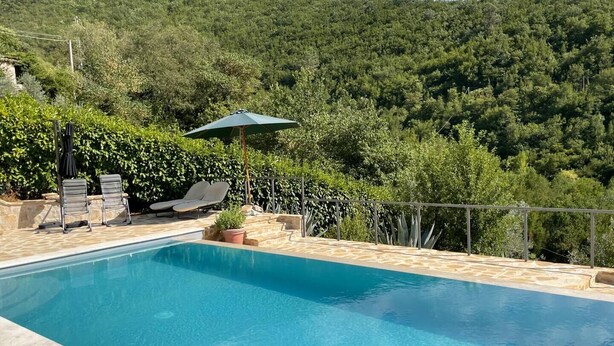 Ein rechteckiger Pool mit Steinbordurand, zwei Liegestühlen, einem kleinen Sonnenschirm und einem Blumentopf.