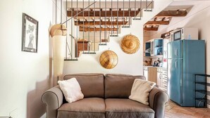 Ein modernes Wohnzimmer mit einem braunen Ledersofa, einem blauen Kühlschrank und einer Treppe mit freiliegenden Holzbalken.