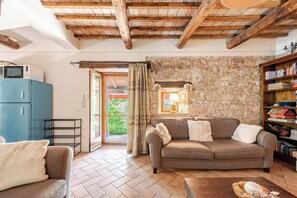 A cozy living room with a stone wall, a wooden ceiling, a blue cabinet, and a bookshelf.