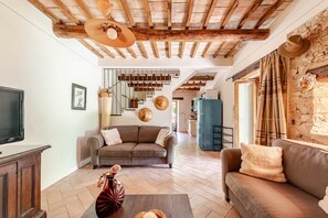 Amplia sala de estar con techo alto, un conjunto de sofás, un televisor y un jarrón decorativo.