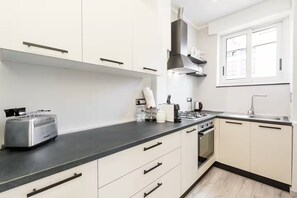 Eine moderne Küche mit weißen Schränken, einer schwarzen Arbeitsplatte, einem Gasherd und einem eingebauten Backofen.