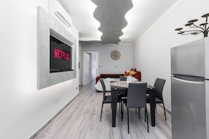 Eine moderne Küche mit einem eingebauten Kühlschrank, einem Essbereich mit Tisch und Stühlen sowie einem an der Wand befestigten Fernseher, der 'NETFLIX' anzeigt.