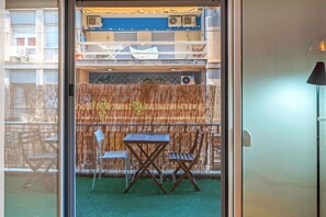 Ein Zimmer mit Glastür, Bambuszaun, zwei Stühlen und einem Tisch.
