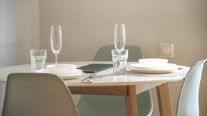 Una mesa de comedor con cuatro sillas, cubiertos y dos copas de vino.