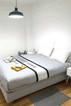 A neatly made bed with a grey and white color scheme, a black accent strip, and a folded towel on the side. - Athens Urban Haven Exarchia (Athina)