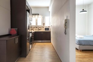 A narrow hallway leading to a kitchen with dark cabinets, a microwave, and a sink. - Athens Urban Haven Exarchia (Athina)