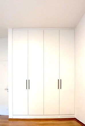 Ein Zimmer mit einem großen, weißen Schrank mit zwei Türen und Holzboden.