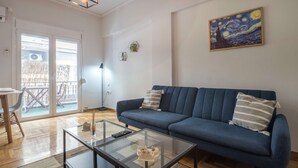 Una sala de estar con un sofá azul, una mesa de centro de vidrio y un cuadro en la pared.