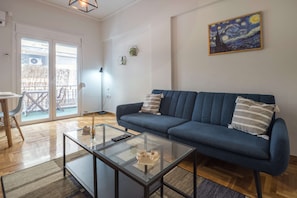 A living room with a blue sofa, a glass coffee table, and a painting on the wall. - Athens Urban Haven Exarchia (Athina)