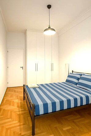 Une chambre à coucher avec un lit, une armoire et un luminaire suspendu.