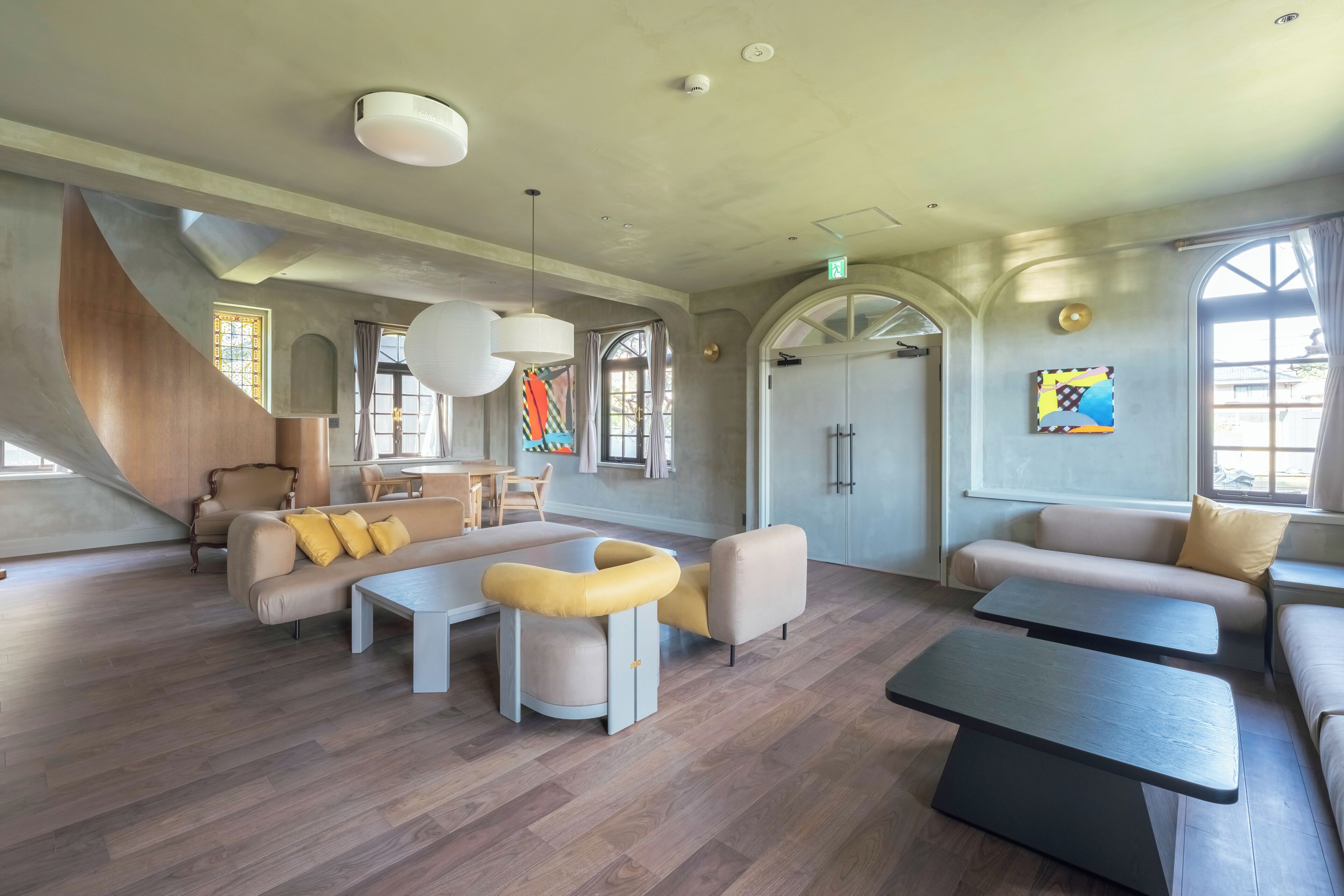 Ett rymligt loungeområde med modern design, med en stor soffa, ett soffbord och en sittgrupp med ett litet bord.